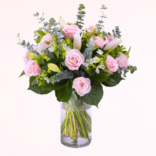 A classic and elegant design featuring roses, premium lilies, and elegant mix of greens complete with a elegant glass cylinder vase.