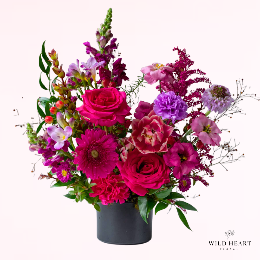 A luscious mix of hot pink premium flowers with roses, double tulips, lisianthus, snapdragons, and pops of lighter colored accent bloom and foliage